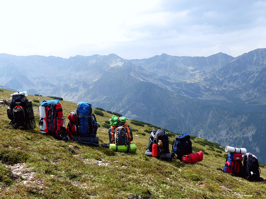 A row of backpacks and the Parâng Mountains in the Background.